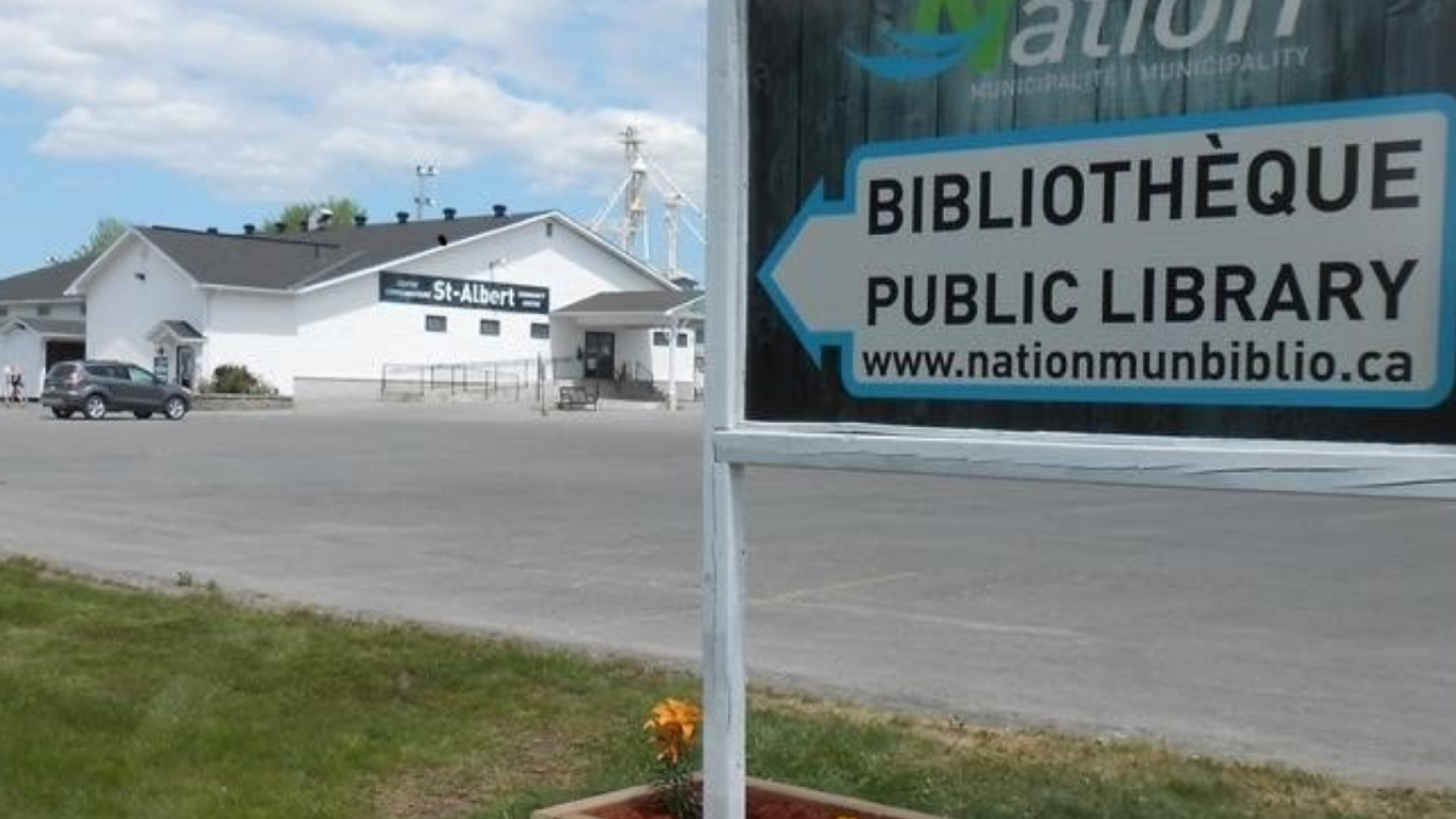 Public library sign with the St-Albert Branch white building in the background.