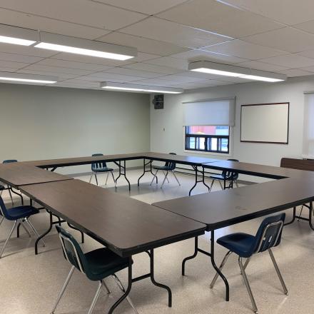 Empty conference room with U-shaped table and blue chairs.