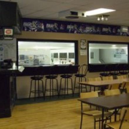 Cafeteria with tables, chairs, counter, and large windows to kitchen.