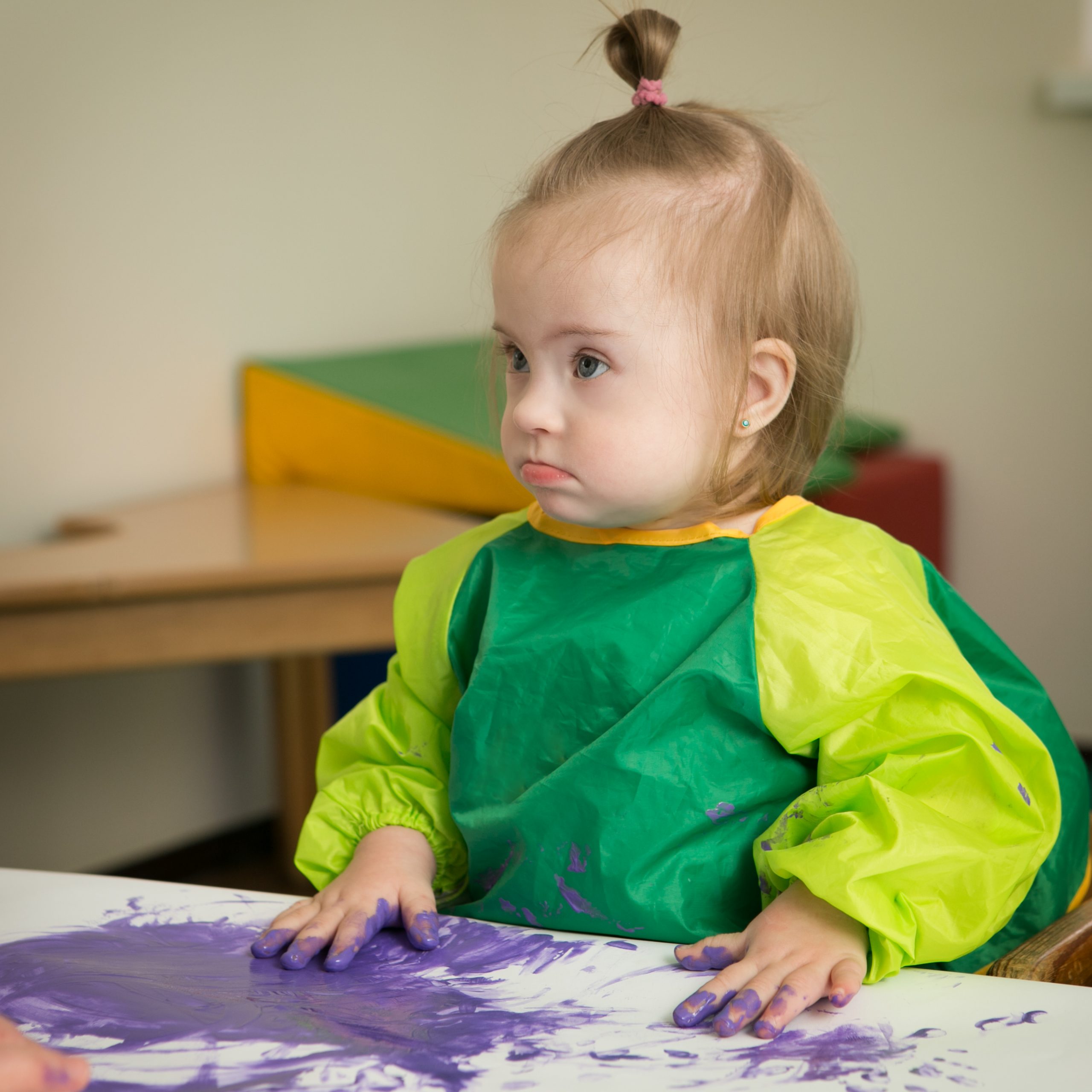 Toddler with Down Syndrome playing at a crafts table.