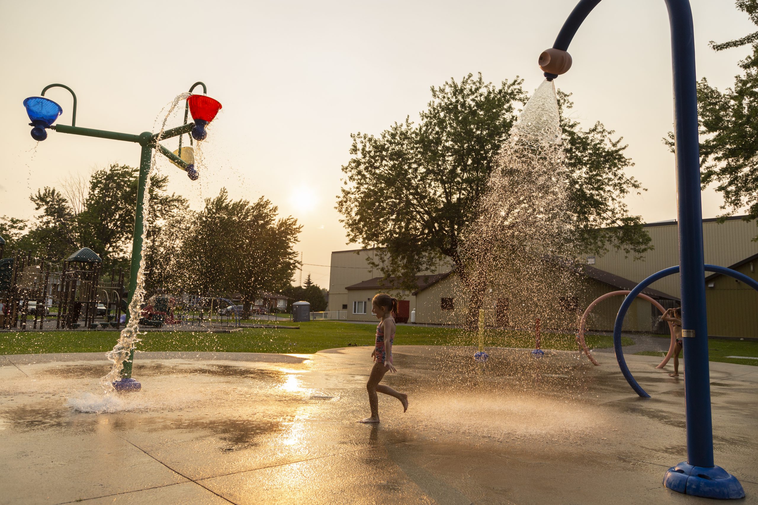 Girl playing in the St-Isidore Splash Pad during sunset
