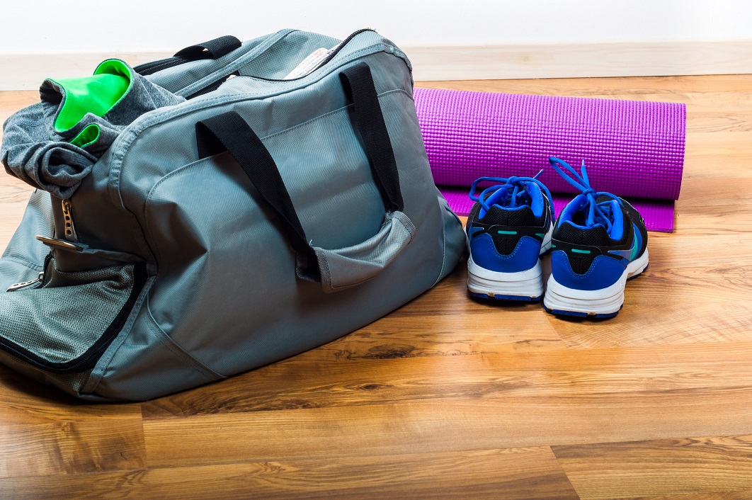 Travel bag with workout shoes and yoga matt beside it 