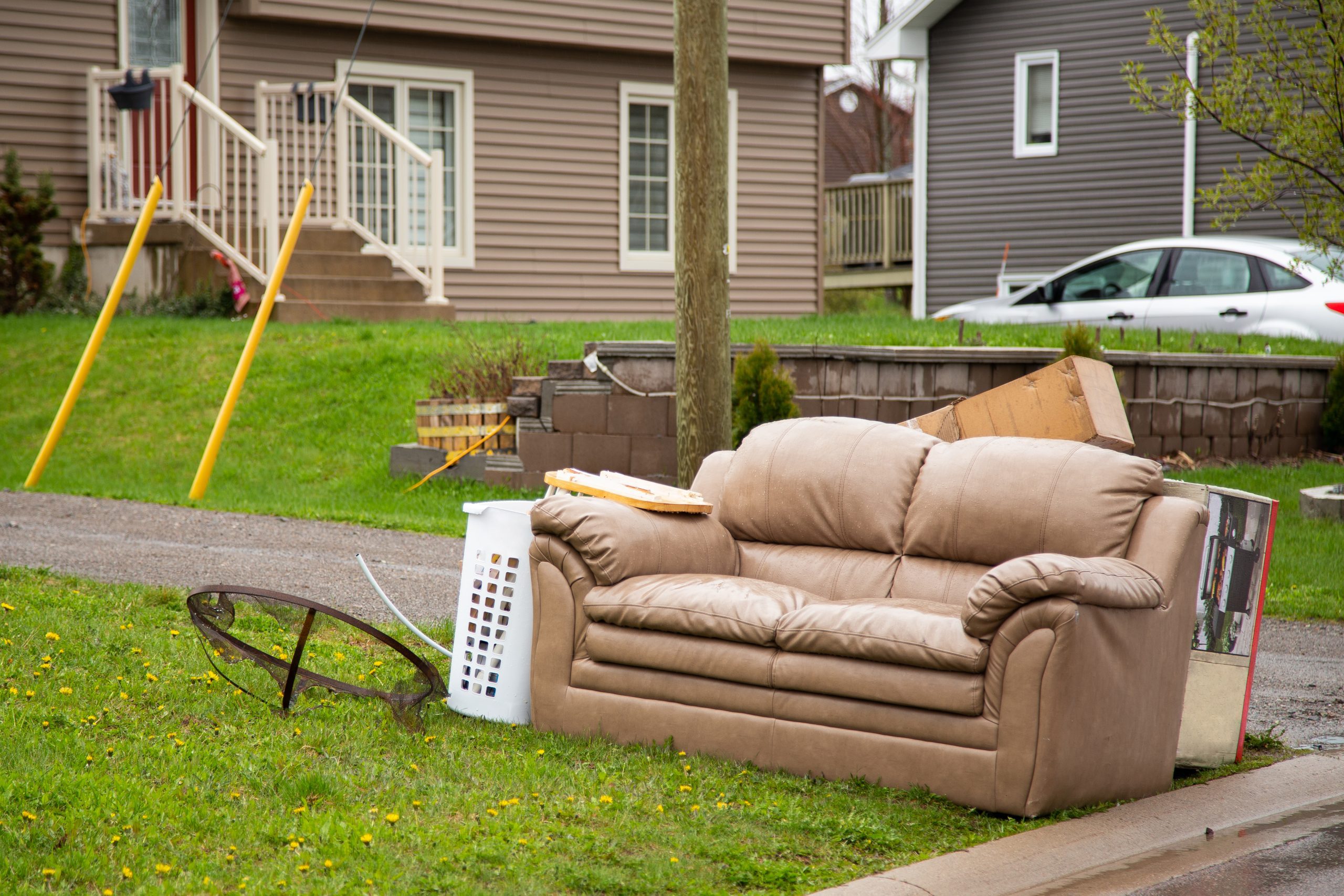 Bulk garbage including a brown couch sitting on a front lawn.